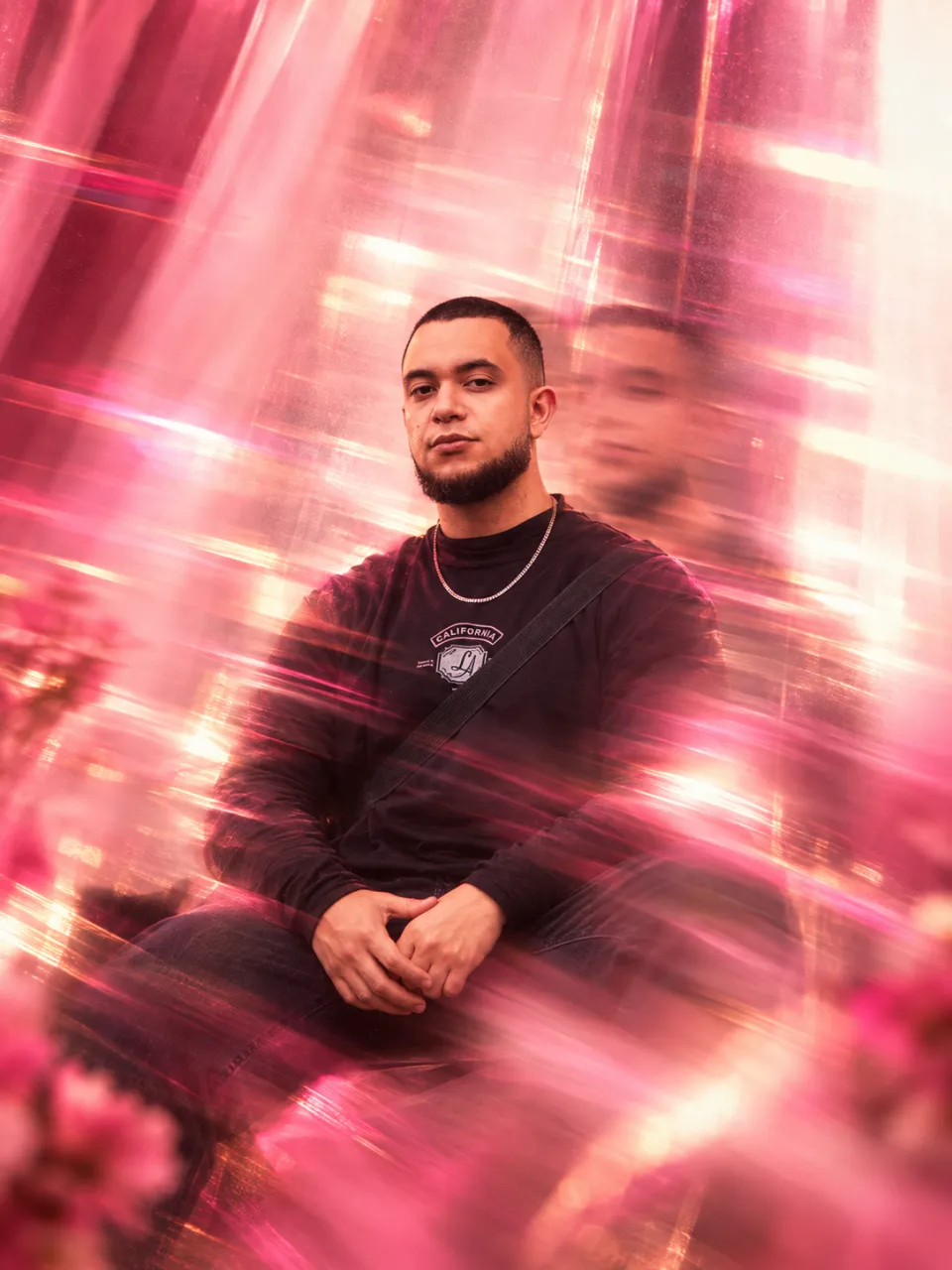 Retrato de Matheus Souza em longa exposição, com rastros de movimento em tons de rosa